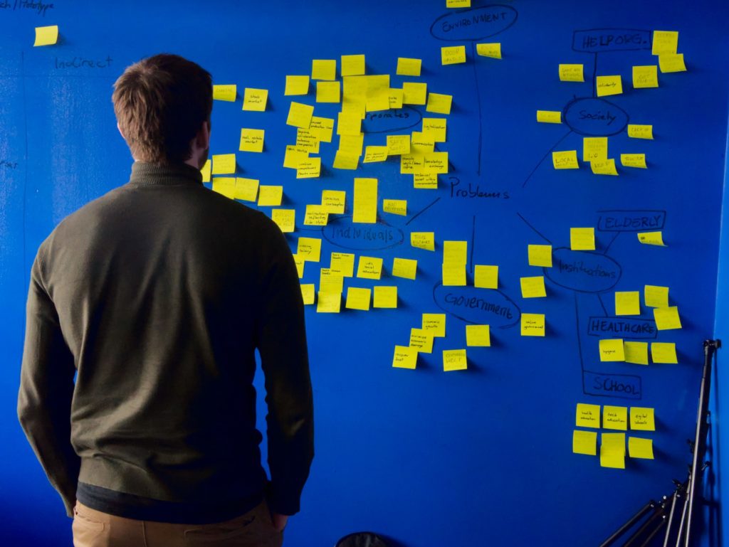 Une personne regarde un mur couvert de post-it